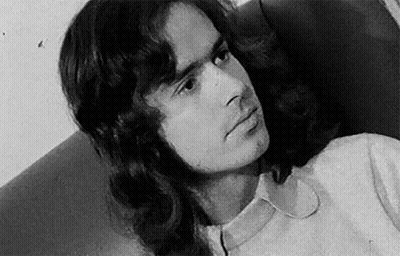A Black And White Photo Of A Man With Long Hair And A White Shirt . GIF