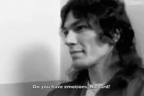 A Black And White Photo Of A Man With Long Hair Talking To Another Man . GIF