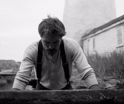 A Black And White Photo Of A Man With Suspenders Looking Down GIF