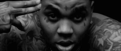 A Black And White Photo Of A Man With Tattoos On His Arms And Face . GIF