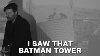 A Black And White Photo Of A Man With The Words I Saw That Batman Tower Below Him GIF
