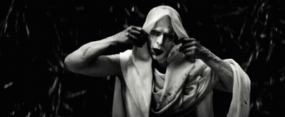 A Black And White Photo Of A Man With White Paint On His Face Holding A White Cloth Over His Head GIF