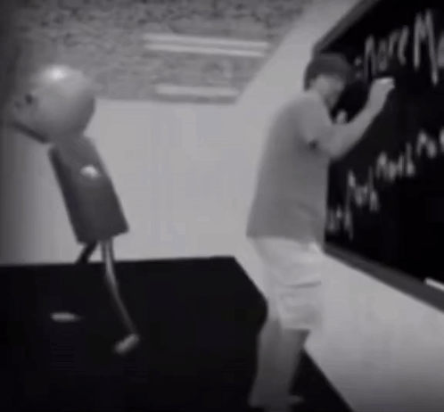A Black And White Photo Of A Man Writing On A Chalkboard GIF