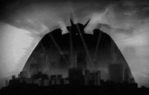 A Black And White Photo Of A Monster Coming Out Of The Sky Over A City GIF