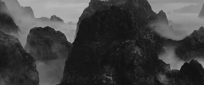 A Black And White Photo Of A Mountain Covered In Fog GIF