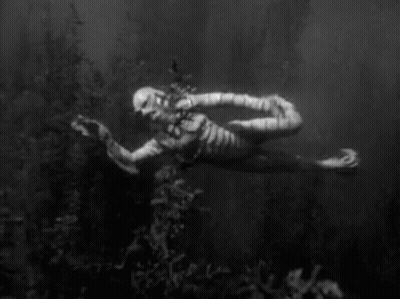 A Black And White Photo Of A Mummy Floating In The Water . GIF