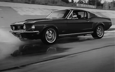 A Black And White Photo Of A Mustang Driving Down A Road GIF