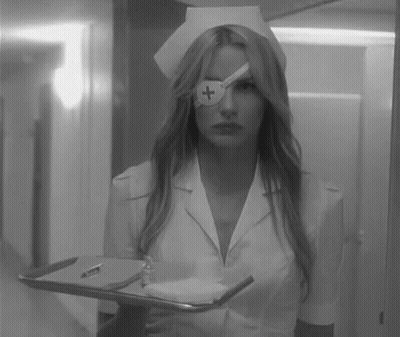 A Black And White Photo Of A Nurse Holding A Tray With A Cross On Her Eye . GIF