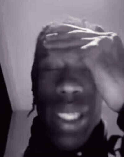 A Black And White Photo Of A Person Covering Their Face With Their Hands . GIF