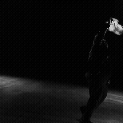 A Black And White Photo Of A Person Dancing In Front Of A Row Of Speakers GIF