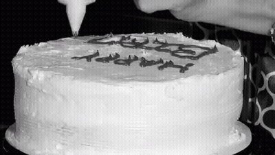 A Black And White Photo Of A Person Frosting A Cake With Icing . GIF