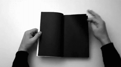 A Black And White Photo Of A Person Holding A Black Book Open . GIF