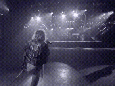 A Black And White Photo Of A Person Holding A Microphone GIF