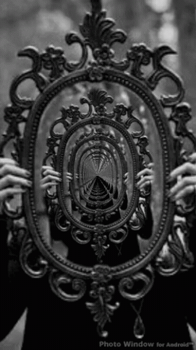 A Black And White Photo Of A Person Holding A Mirror With A Reflection Of A Tunnel In It GIF