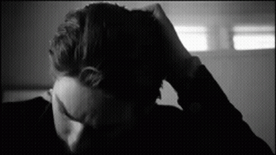 A Black And White Photo Of A Person Holding Their Head . GIF