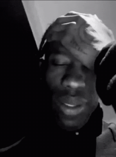 A Black And White Photo Of A Person Holding Their Head . GIF