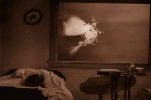 A Black And White Photo Of A Person Laying On A Bed In A Room . GIF