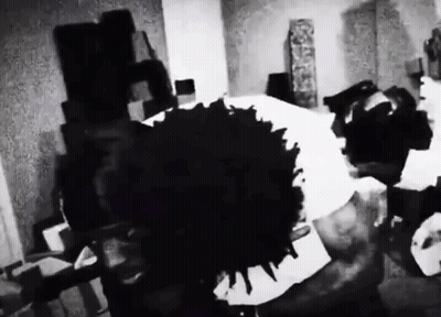 A Black And White Photo Of A Person Laying On A Bed With A Large Black Spot On The Floor . GIF
