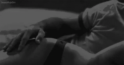 A Black And White Photo Of A Person Laying On A Bed With Their Hands On Their Stomach . GIF