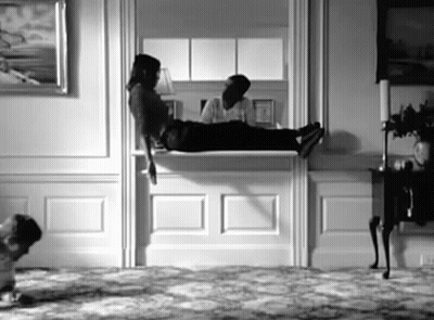 A Black And White Photo Of A Person Laying On A Mantle In A Living Room . GIF
