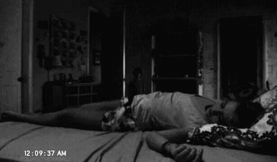 A Black And White Photo Of A Person Laying On Their Back On A Bed In A Dark Room . GIF
