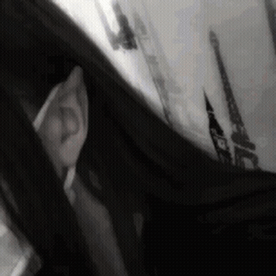 A Black And White Photo Of A Person Looking Out Of A Window GIF