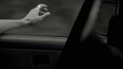 A Black And White Photo Of A Person 'S Hand Reaching Out From A Car Window GIF