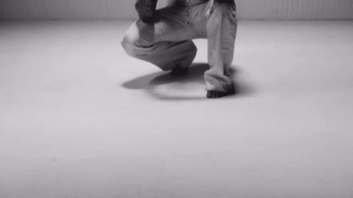 A Black And White Photo Of A Person Squatting On A White Surface GIF