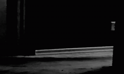 A Black And White Photo Of A Person Standing In A Dark Room . GIF