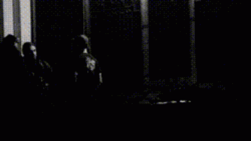 A Black And White Photo Of A Person Standing On Stairs At Night GIF