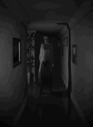 A Black And White Photo Of A Person Walking Down A Hallway GIF