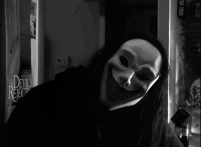 A Black And White Photo Of A Person Wearing A Mask In Front Of A Devils Rejects Sign GIF