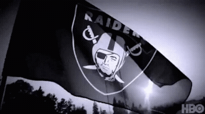 A Black And White Photo Of A Raiders Flag Flying In The Wind GIF