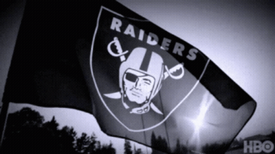 A Black And White Photo Of A Raiders Flag Waving In The Wind GIF