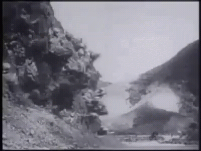 A Black And White Photo Of A Road Going Through A Mountain Valley . GIF