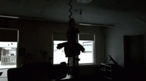 A Black And White Photo Of A Room With A Silhouette Of A Person Hanging From The Ceiling GIF