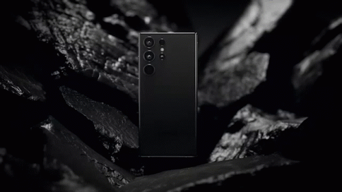 A Black And White Photo Of A Samsung Phone Laying On A Rock GIF