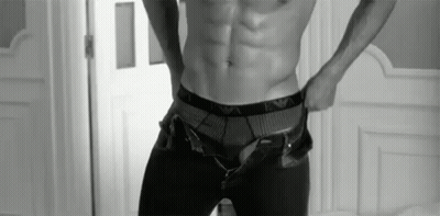 A Black And White Photo Of A Shirtless Man Taking Off His Pants GIF