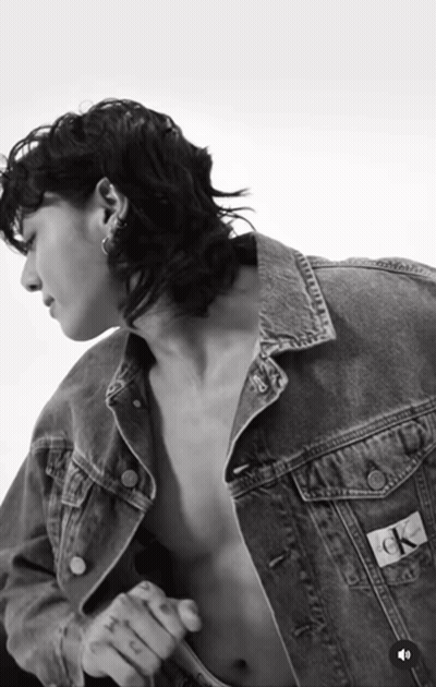A Black And White Photo Of A Shirtless Man Wearing A Denim Jacket That Says Ck On The Back GIF