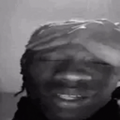 A Black And White Photo Of A Smiling Man Wearing A Hat . GIF