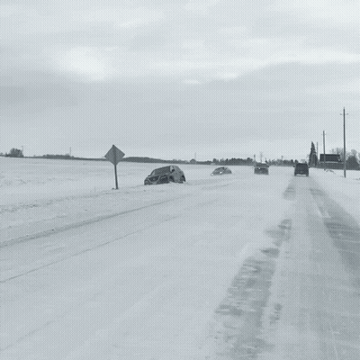 A Black And White Photo Of A Snowy Road With A Police Car In The Background GIF