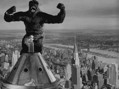 A Black And White Photo Of A Statue Of A Gorilla On Top Of A Building GIF