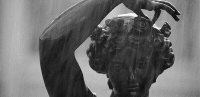 A Black And White Photo Of A Statue Of A Woman With Her Hand On Her Head GIF
