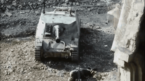 A Black And White Photo Of A Tank Sitting In The Dirt . GIF