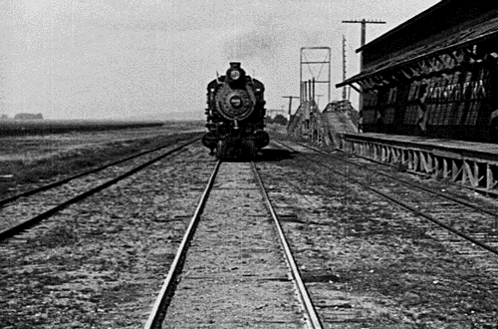 A Black And White Photo Of A Train On The Tracks GIF