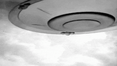 A Black And White Photo Of A Ufo Flying Through The Sky . GIF