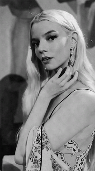 A Black And White Photo Of A Woman Adjusting Her Earrings GIF
