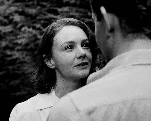 A Black And White Photo Of A Woman And A Man Looking At Each Other GIF