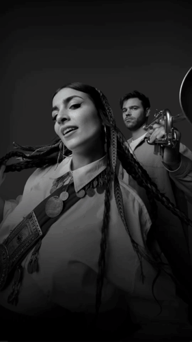 A Black And White Photo Of A Woman And A Man Playing Trumpets GIF
