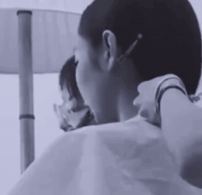 A Black And White Photo Of A Woman Getting Her Hair Cut By A Hairdresser . GIF